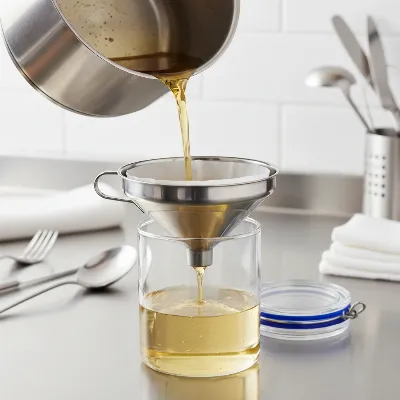Deep fryer oil being filtered into a clean storage container